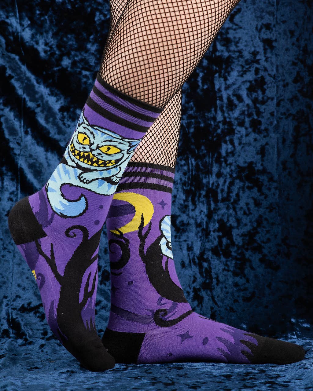 A model wearing a pair of socks featuring the cheshire cat. Purple legs, black heel, cuff and toe.