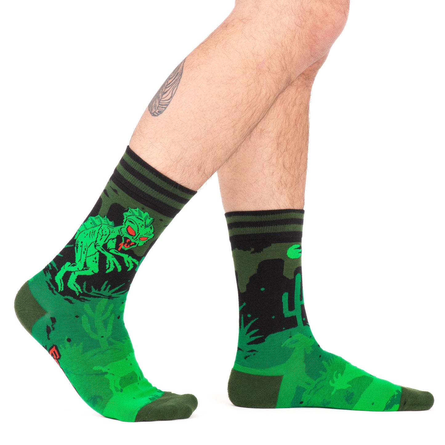 A model wearing a pair of socks featuring El Chupacabra. Green legs, heel, toe and cuff.