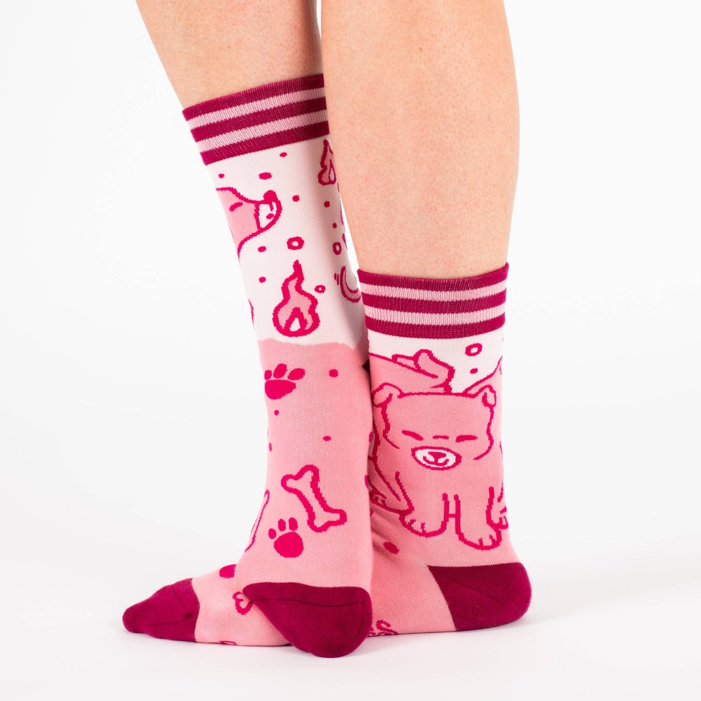 A model wearing a pair of socks featuring a cute 3 headed dog. Pink legs, dark pink heel, toe and cuff.