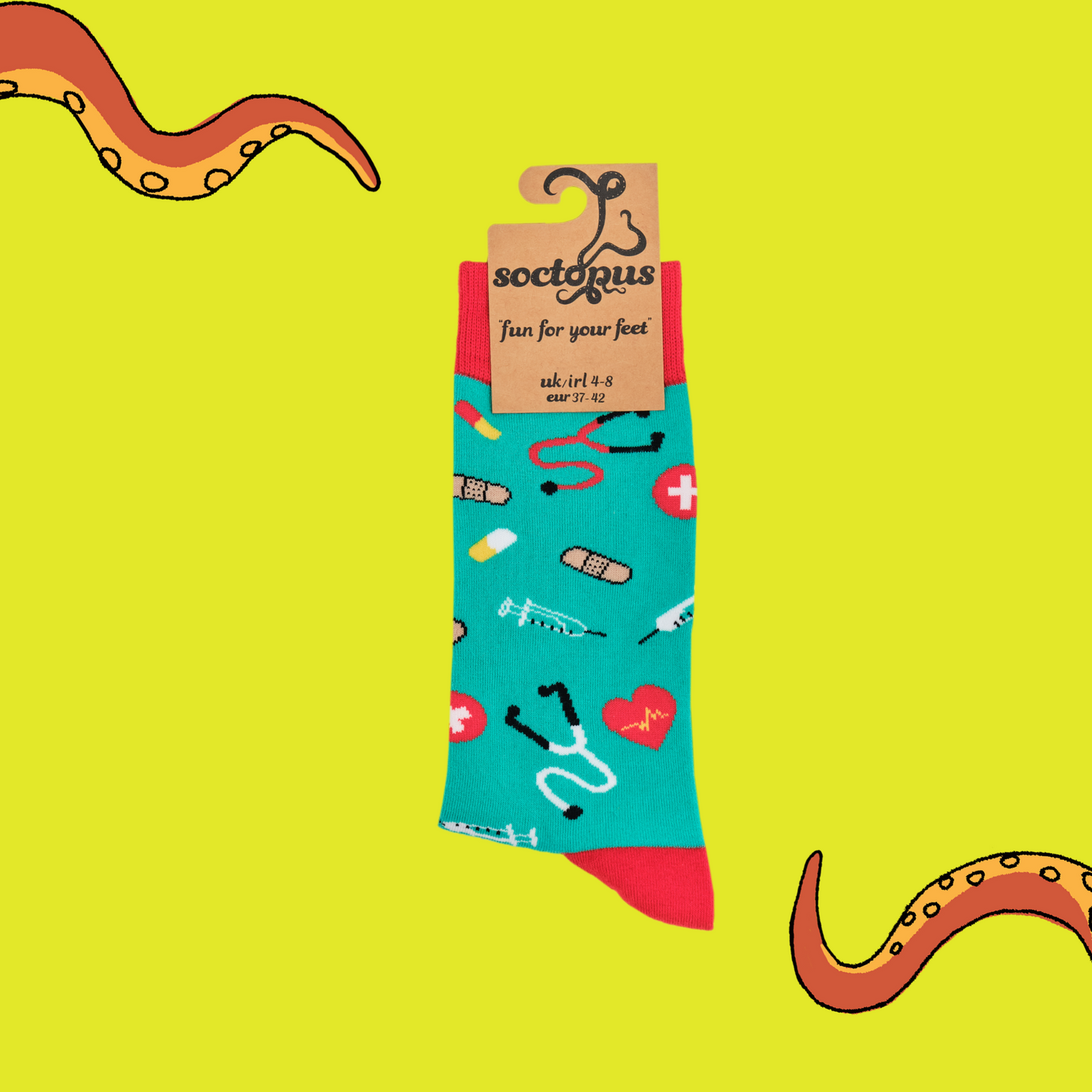 A pair of socks depicting medical equipment and symbols. Green legs, red cuff, heel and toe. In Soctopus Packaging.