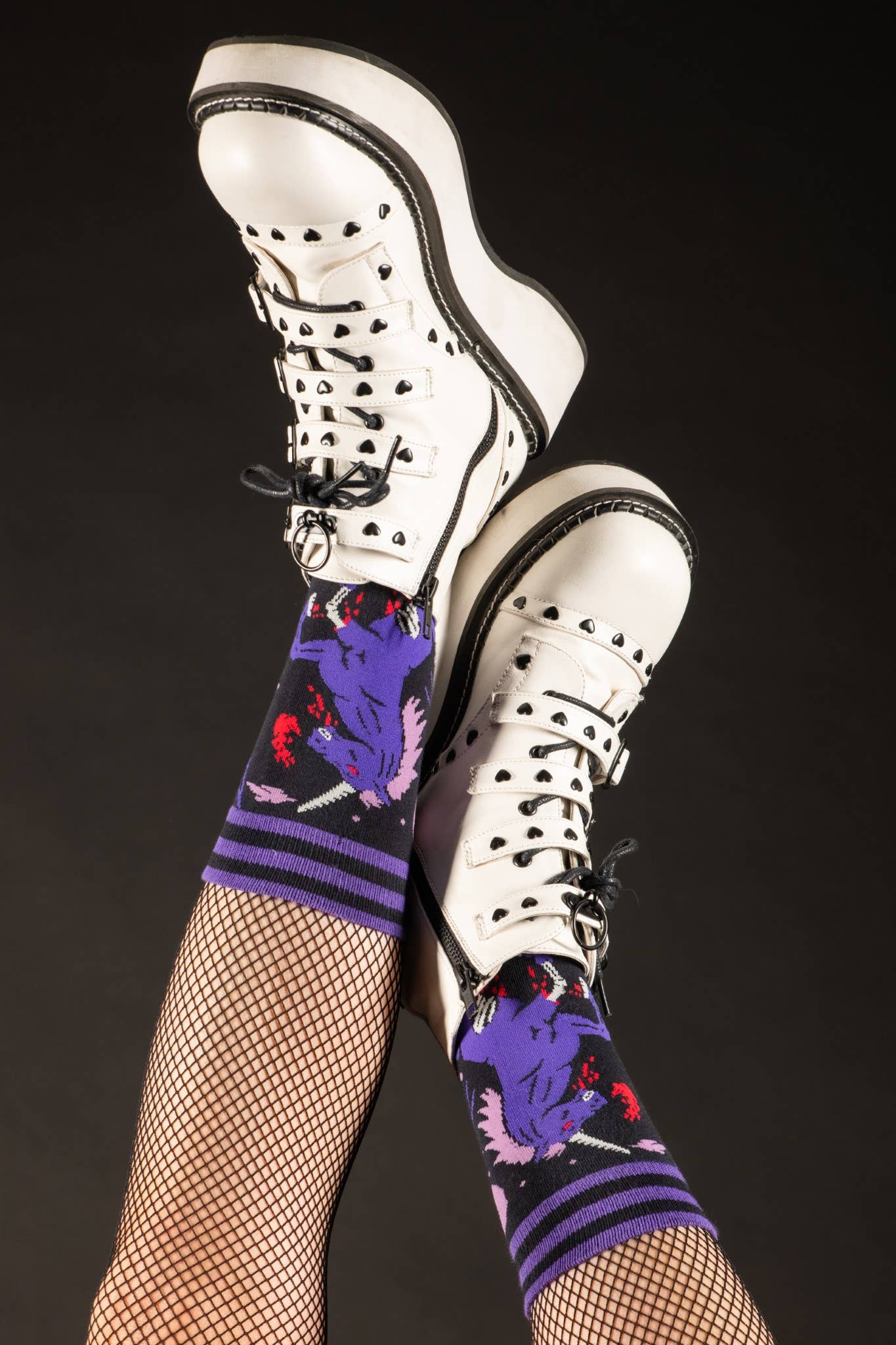 Model wearing a pair of socks with a dark and twisted unicron motif. Pink and purple legs, black heel, toe and cuff.