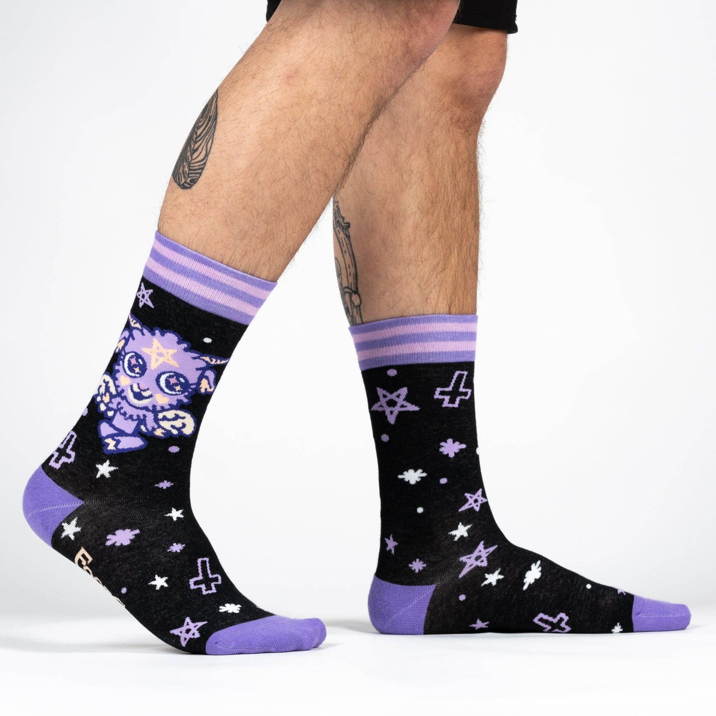 A model wearing a pair of socks depicting a baby version of the dark lord Baphomet. Purple toe, heel and cuff.