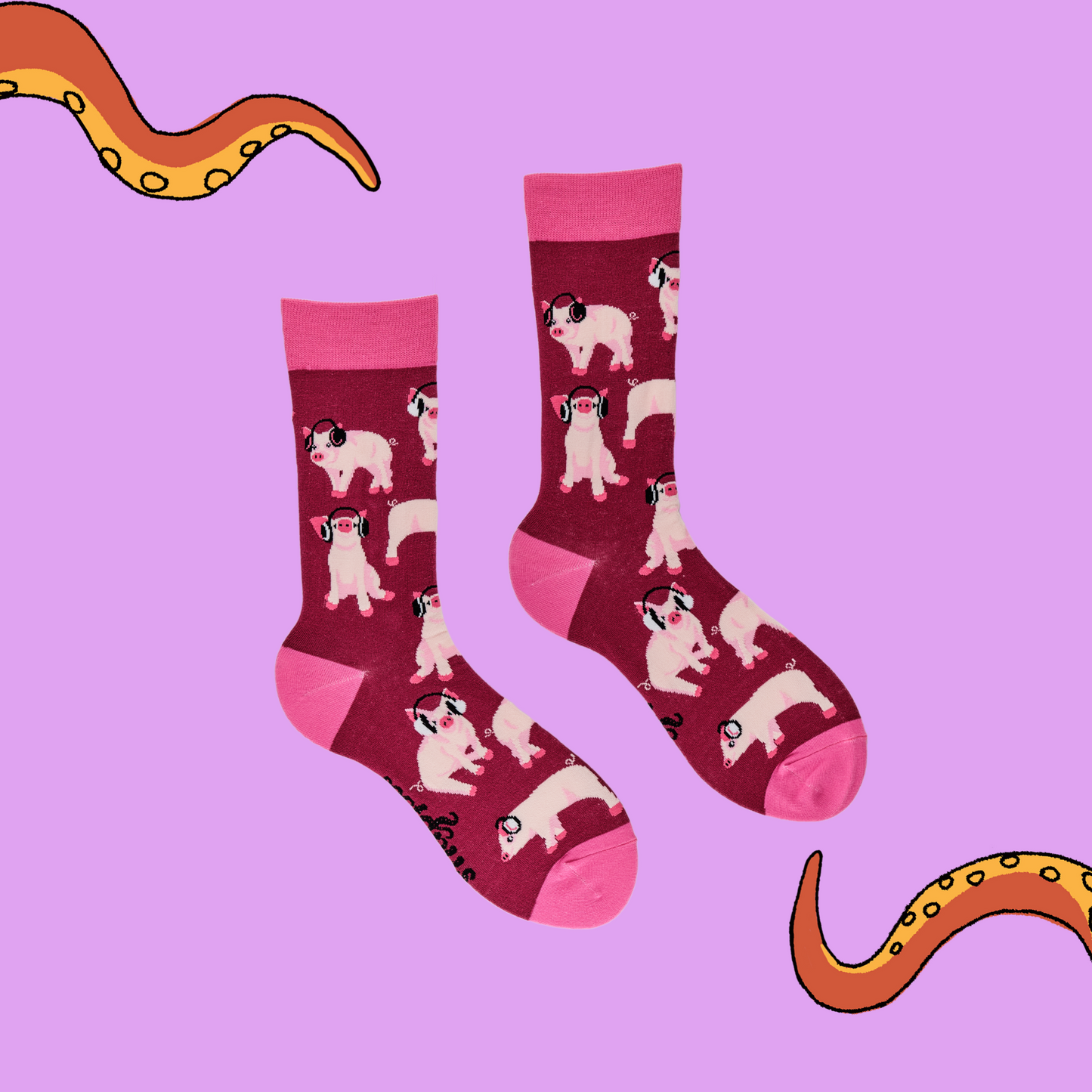 A pair of socks depicting Pigs being wearing headphones. Burgundy legs, pink cuff, heel and toe. Lilac background with Soctopus tentacles.