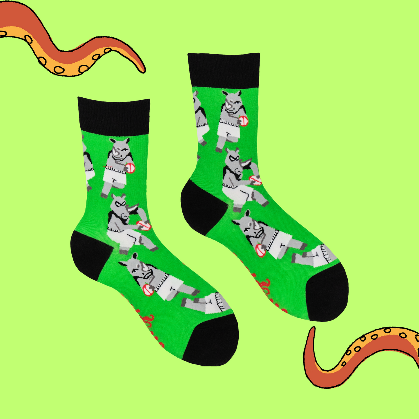 A pair of socks featuring rhinos playing rugby. Green legs, black heel, toe and cuff.