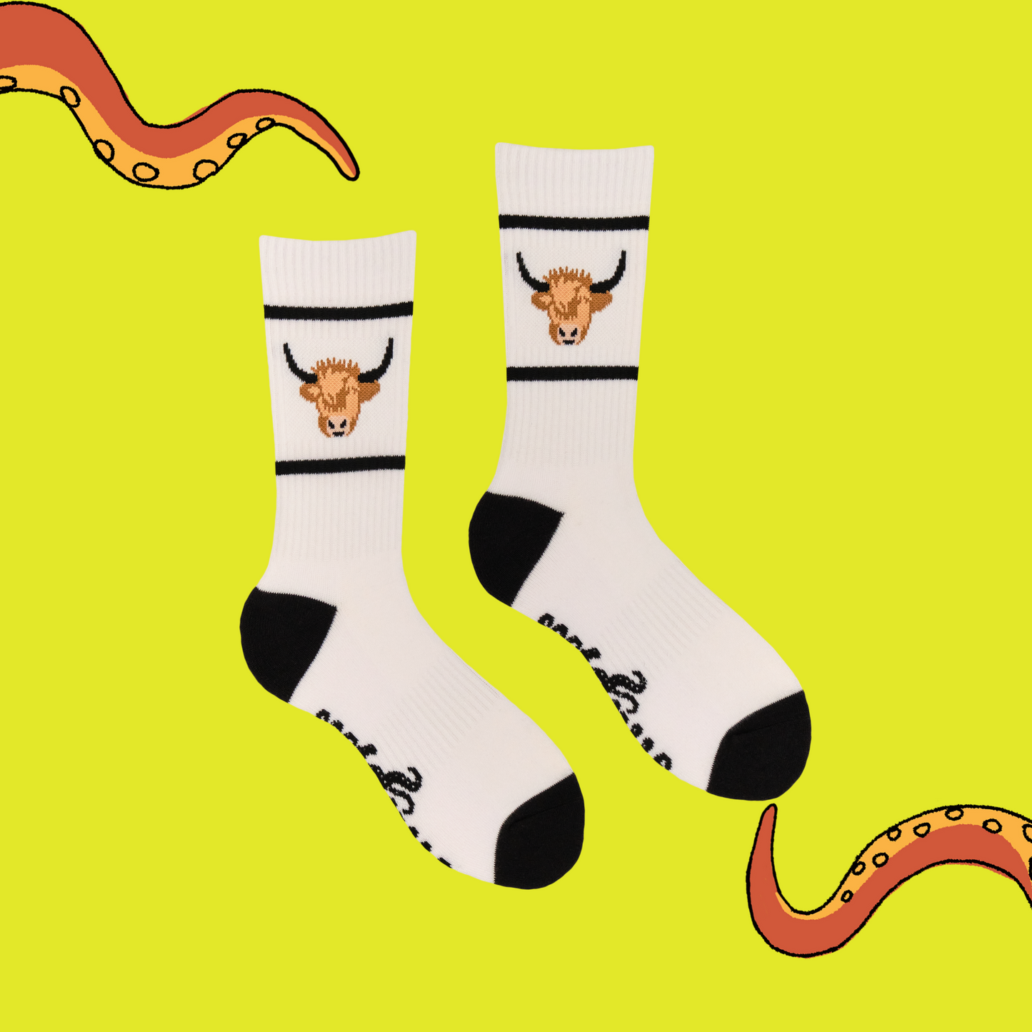 A pair of athletic style socks featuring a highland cow motif. White legs, black eel, toe and cuff.