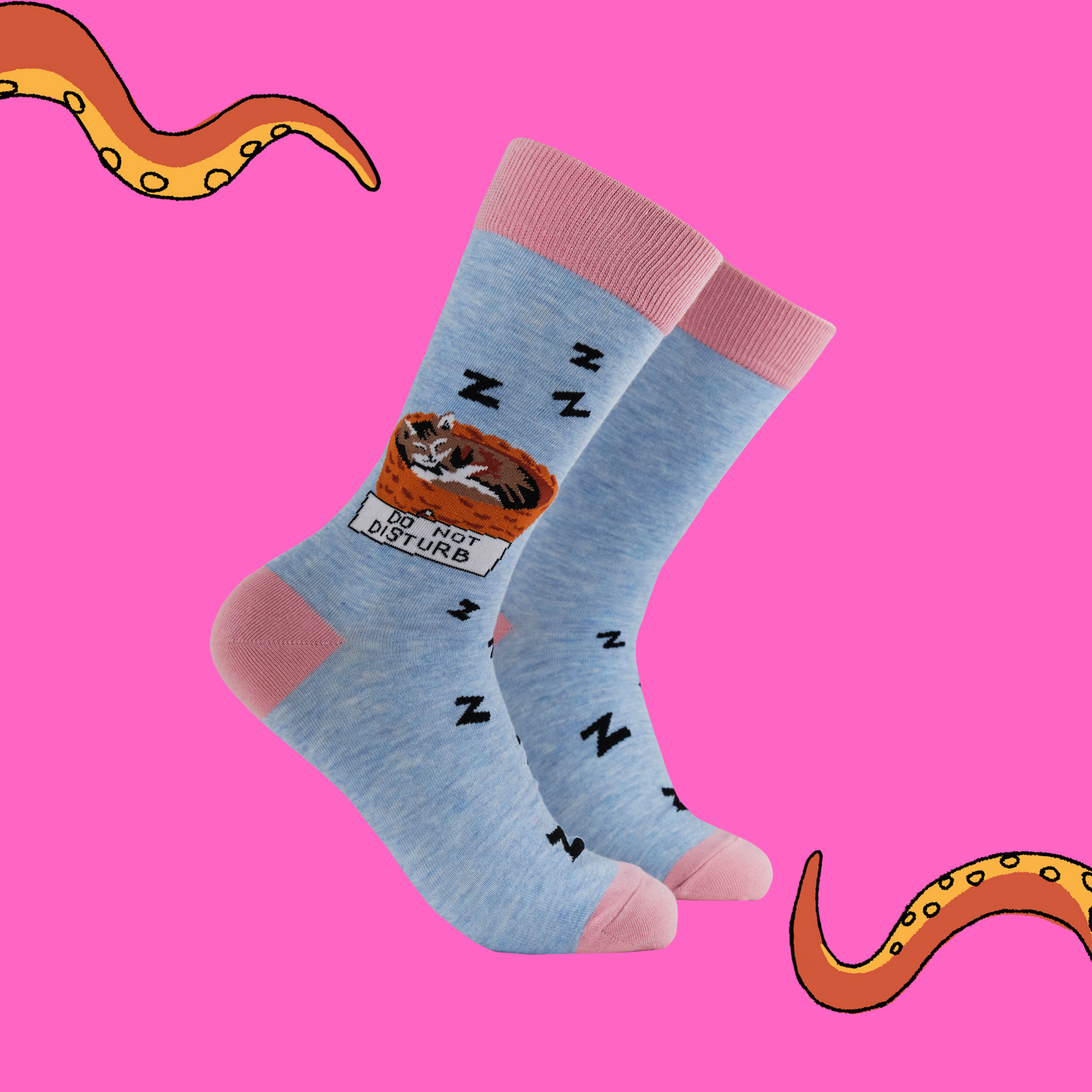 A pair of socks featuring a cat napping in a basket. Blue legs, pink heel, toe and cuff.