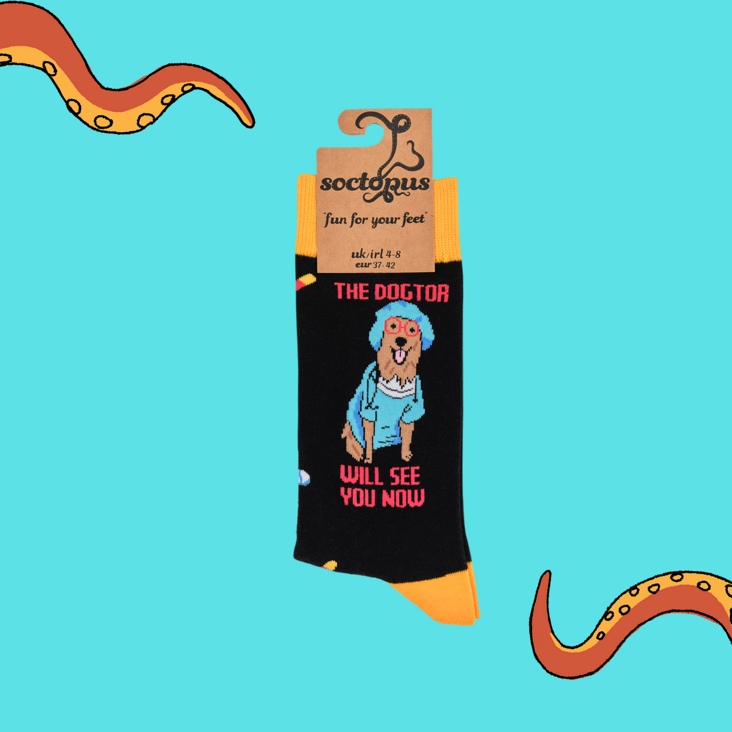 A pair of socks depicting a dog dressed in medical scrubs. Black legs, yellow cuff, heel and toe. In Soctopus Packaging.