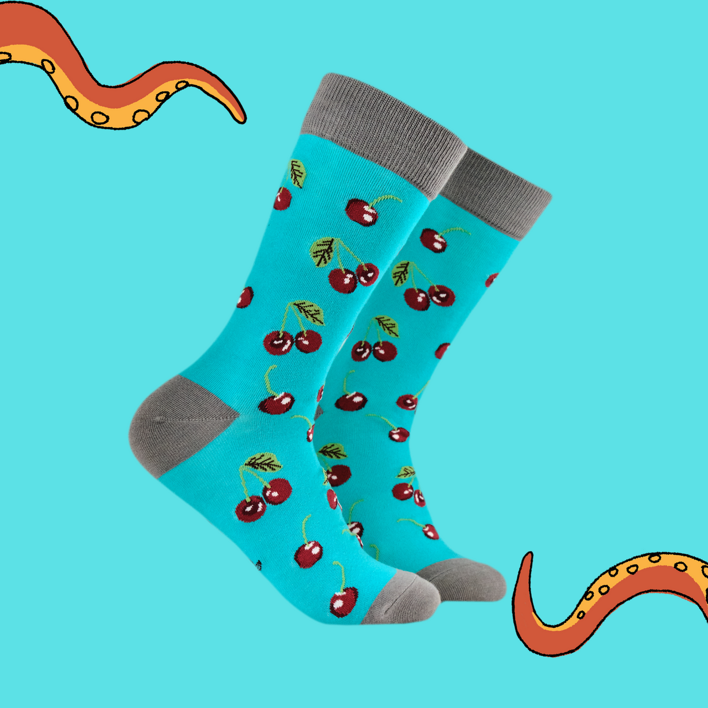 A pair of socks featuring cherries. Bright blue legs, grey heel, toe and cuff.