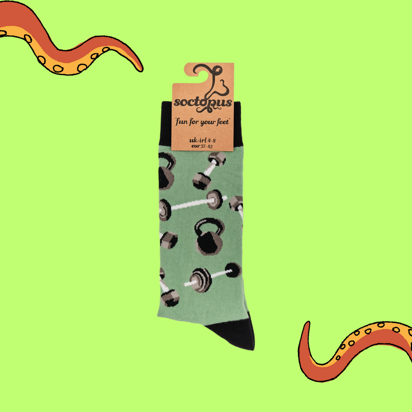 A pair of socks depicting dumb bells and kettle bells. Green legs, black cuff, heel and toe. In Soctopus Packaging.