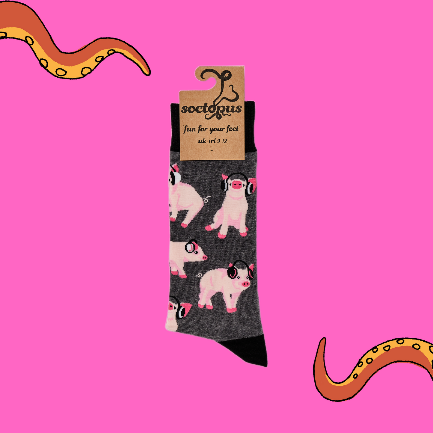 A pair of socks depicting Pigs being wearing headphones. Grey legs, black cuff, heel and toe. In Soctopus packaging. Pink background with Soctopus tentacles.