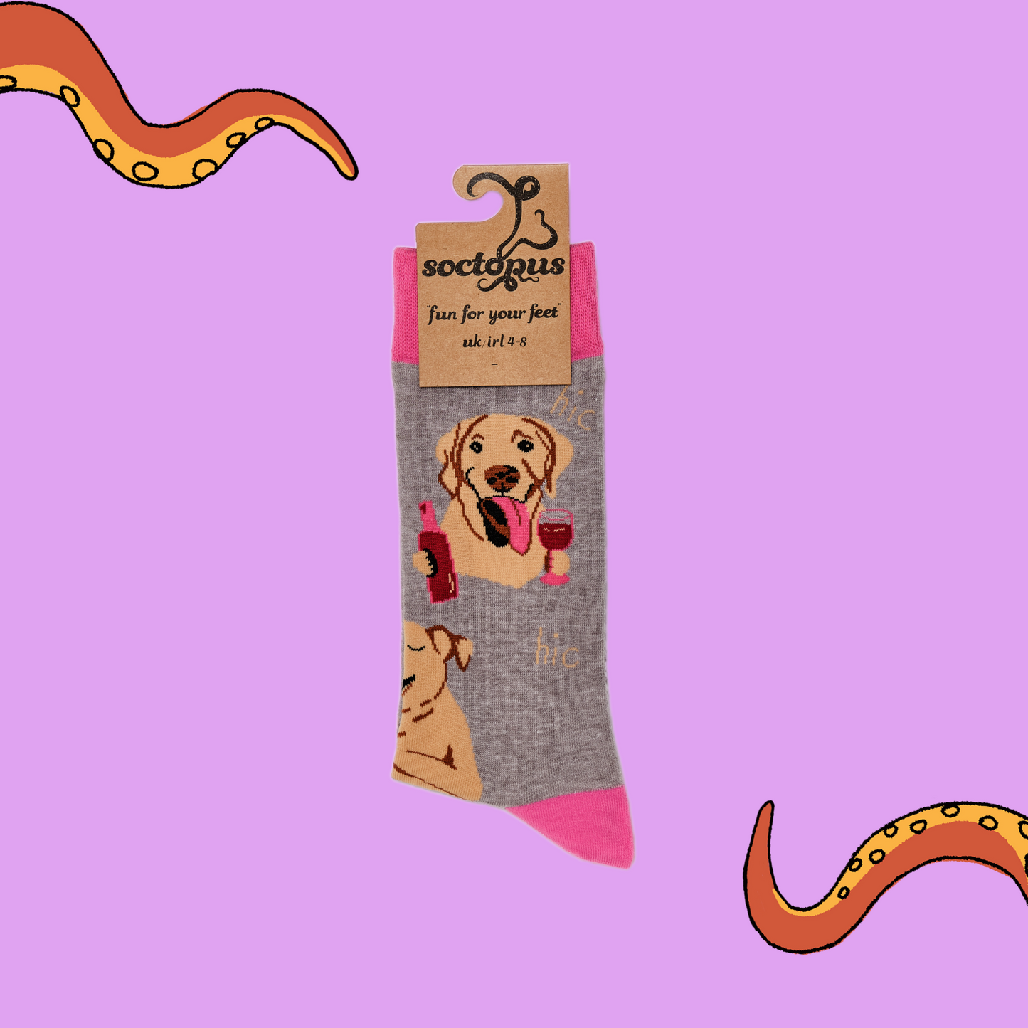 A pair of socks depicting labs drinking wine. Grey legs, light pink cuff, heel and toe. In Socktopus Packaging.