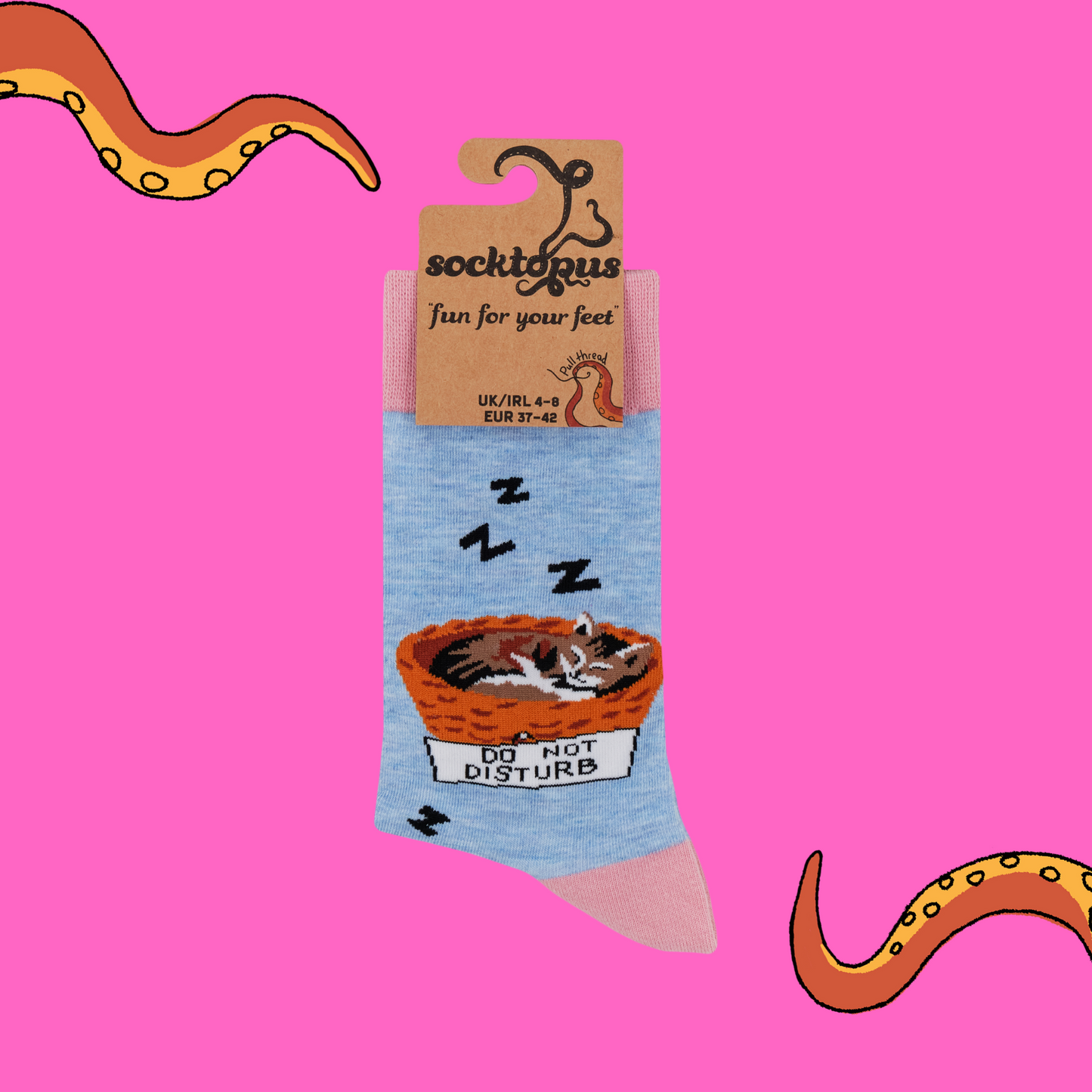 A pair of socks featuring a cat napping in a basket. Blue legs, pink heel, toe and cuff.