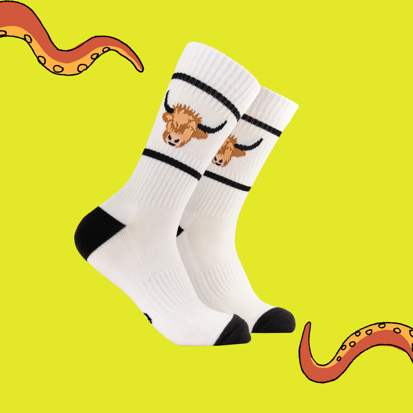 A pair of athletic style socks featuring a highland cow motif. White legs, black eel, toe and cuff.
