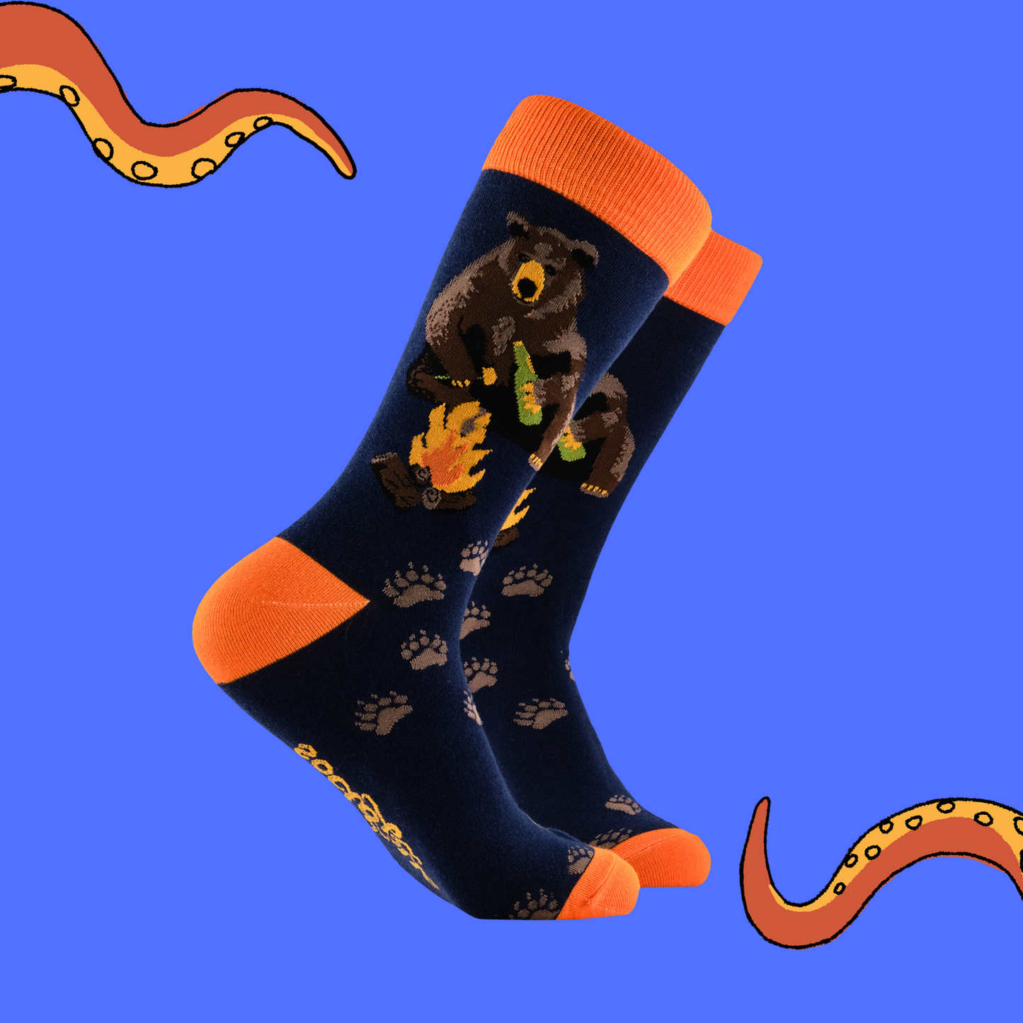 A pair of socks depicting a bear sitting by a campfire. Dark blue legs, orange cuff, heel and toe.