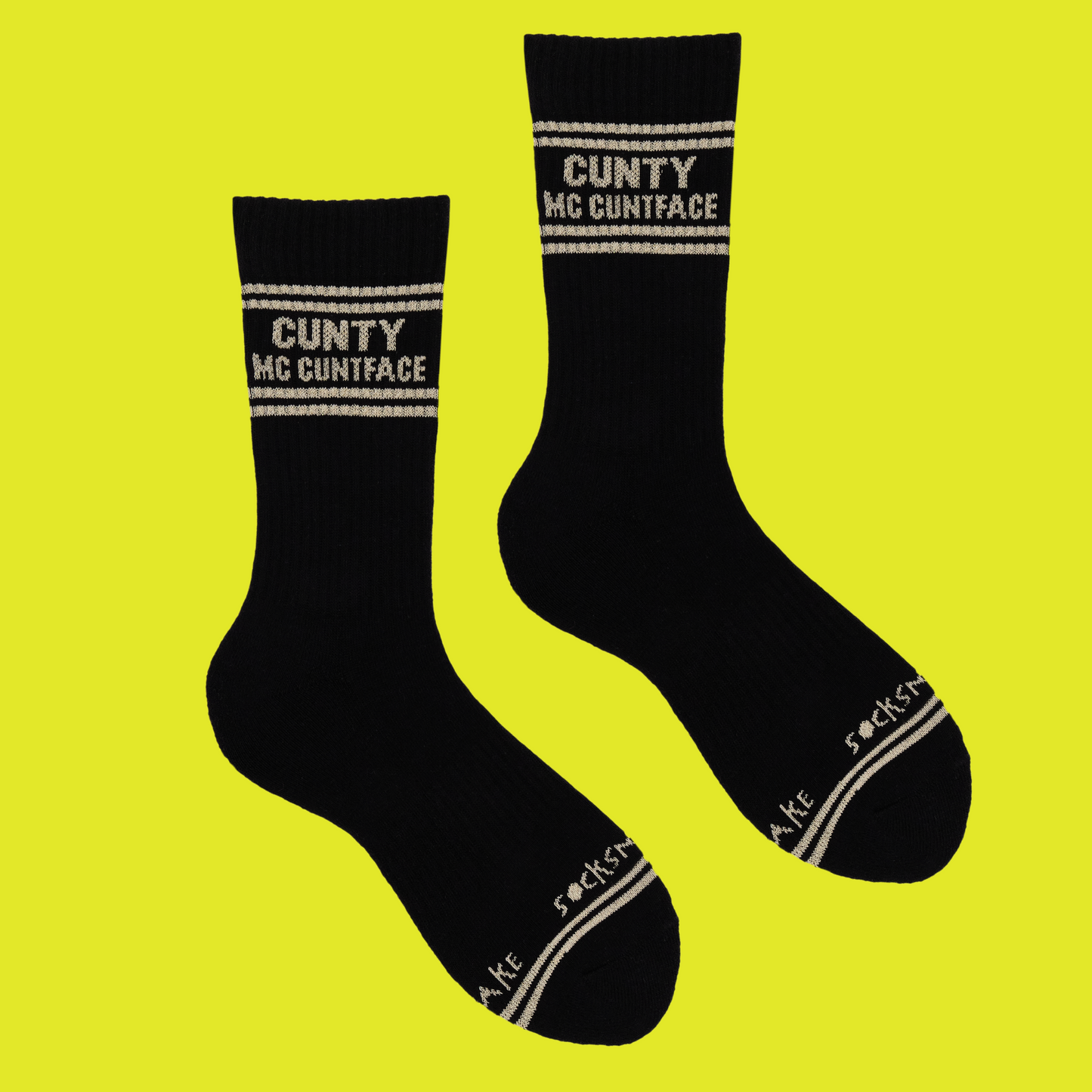 A black pair of athletic socks with white trim on the ankles and toes. With some very rude words on the ankle.