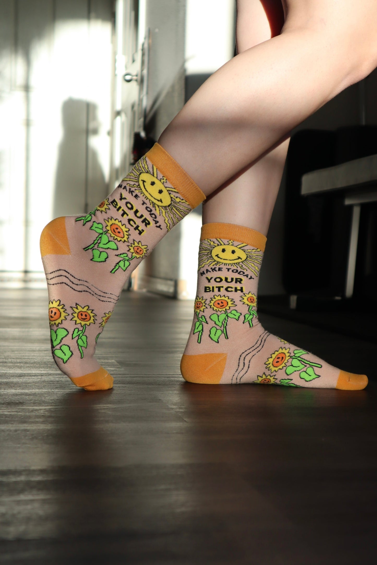 Make Today Your B**tch Socks. A pair of socks depicting the sun and sunflowers with a bold sweary slogan. Orange toes, cuff and heel.