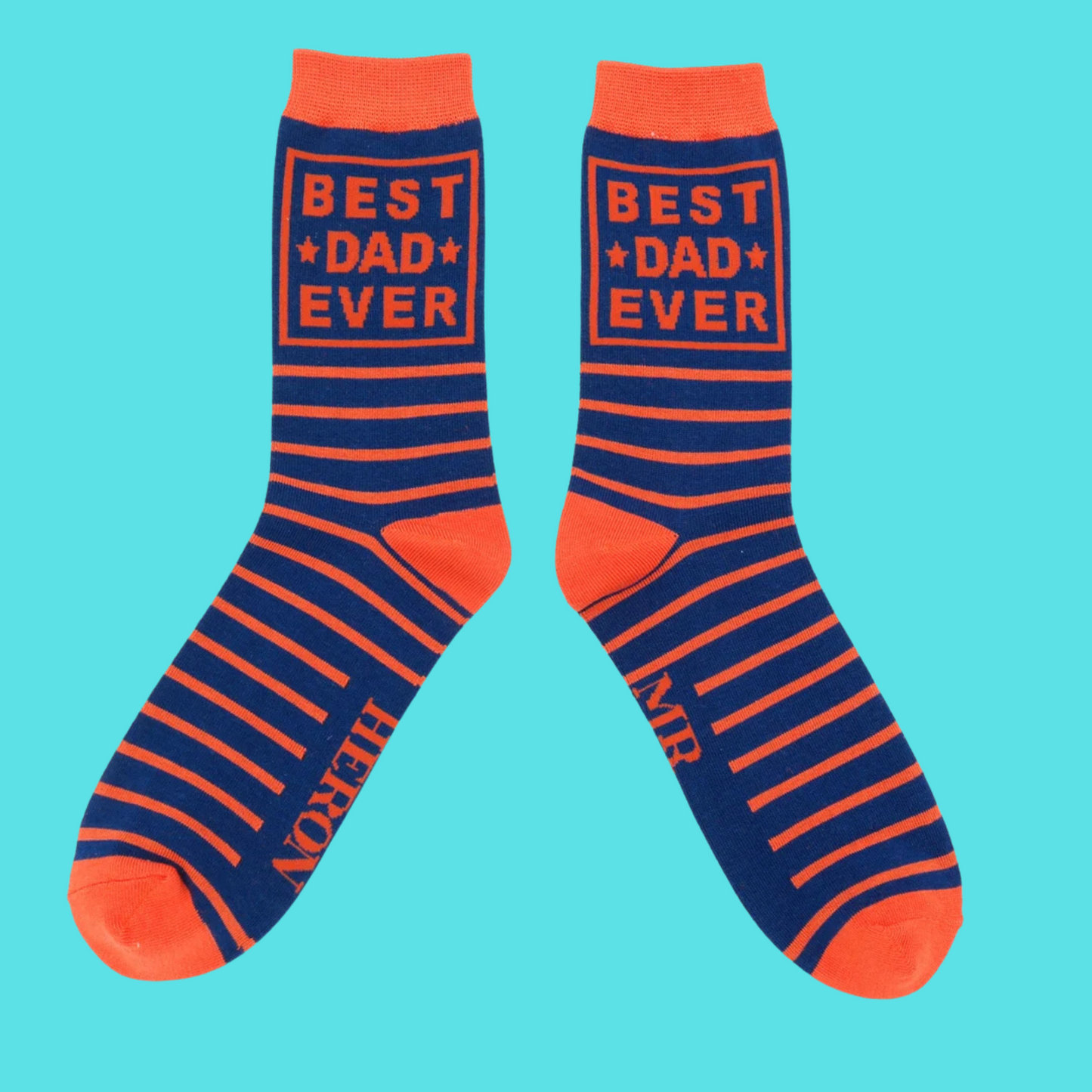 Best Dad Ever Bamboo Socks - Miss Sparrow. A pair of navy socks featuring orange 'Best Dad Ever' slogan and horizontal orange stripes. Orange cuffs, heels, and toes. Socks shown on a turquoise background.