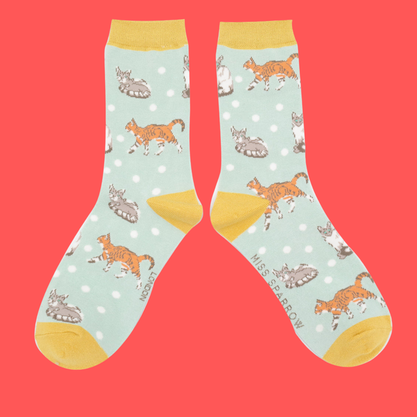 A pair of socks with a cat motif and spots pattern. Light blue legs, yellow heel, toe and cuff.