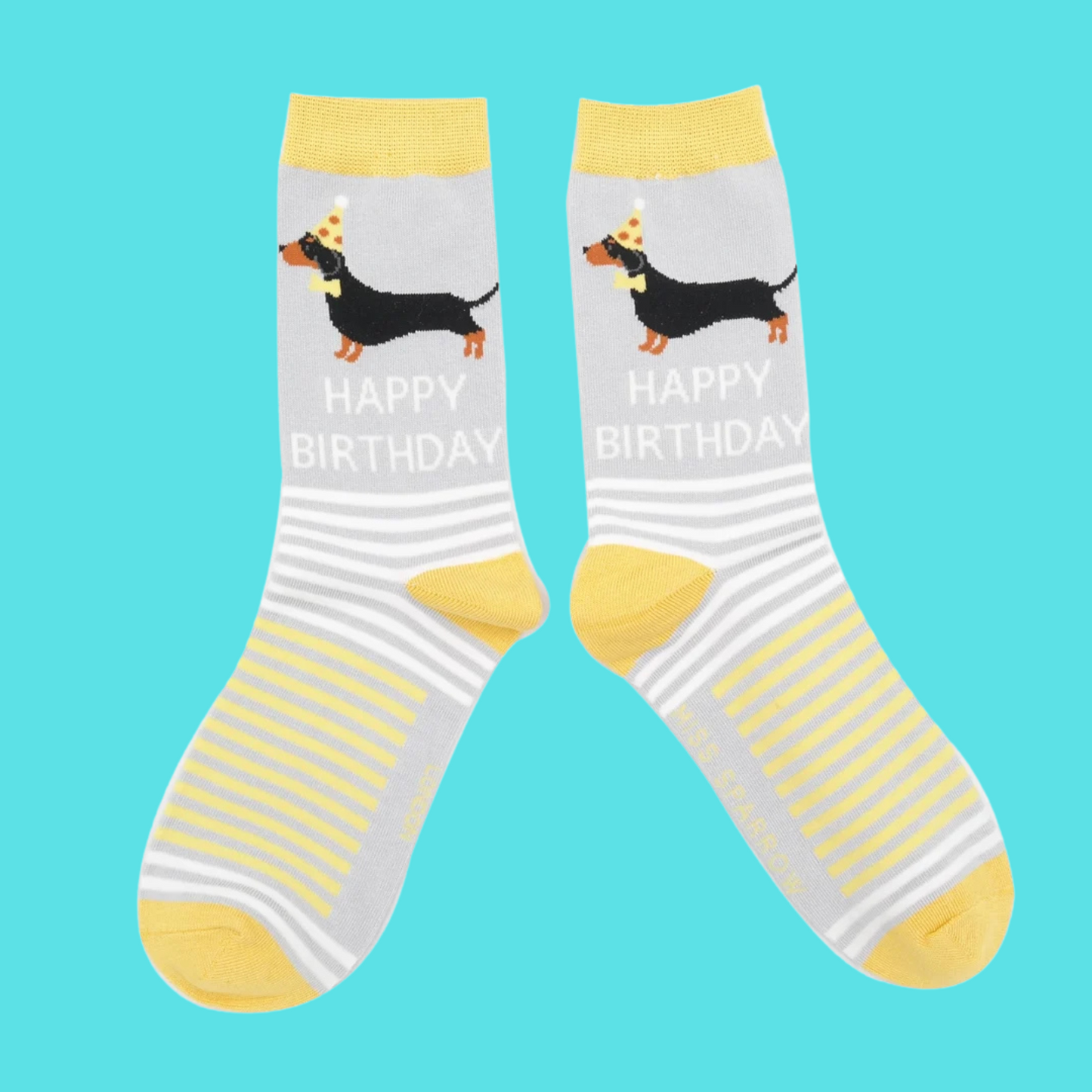 A pair of socks featuring sausage dogs all dressed up for a party. Grey legs, yellow heel, toe and cuff.