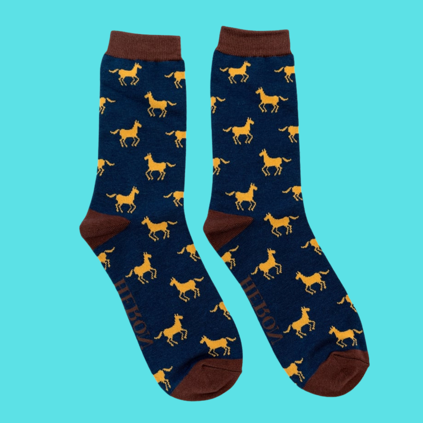 Horses Bamboo Socks - Miss Sparrow. A pair of navy socks featuring a yellow horse pattern. Brown cuffs, heels, and toes. Socks shown on a turquoise background.