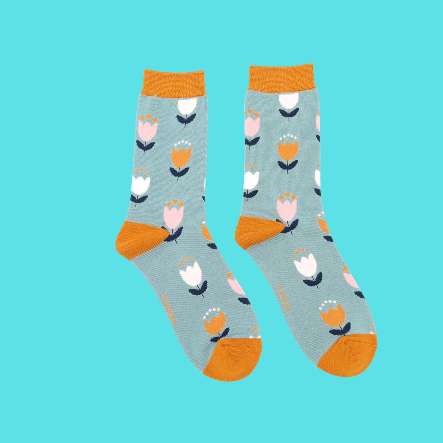 Tulip Bamboo Socks - Miss Sparrow. A pair of pale blue socks featuring a white, yellow, and navy tulip pattern. Yellow cuffs, heels, and toes. Socks shown on a turquoise background.