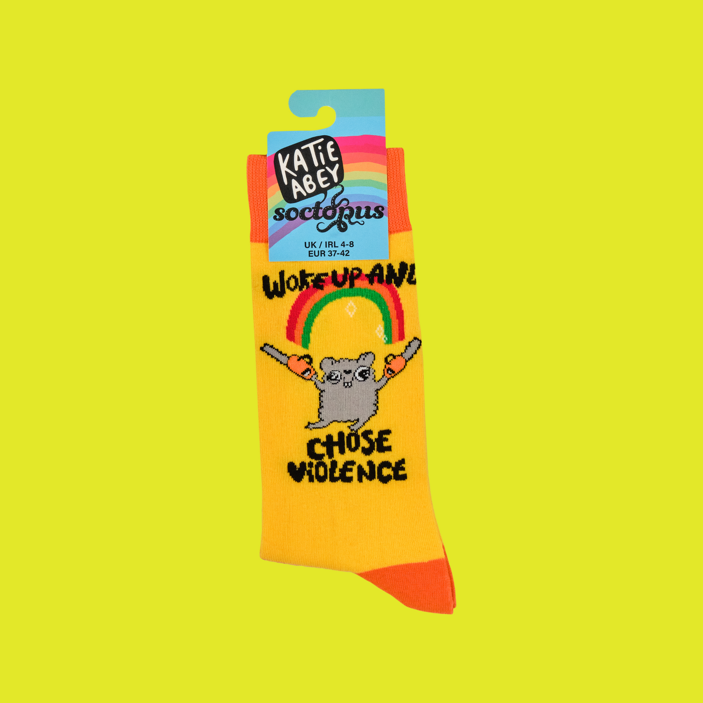A pair of socks depicting a mouse holding chainsaws with the slogan 'woke up and chose violence'. Yellow striped legs, orange toe cuff and heel.