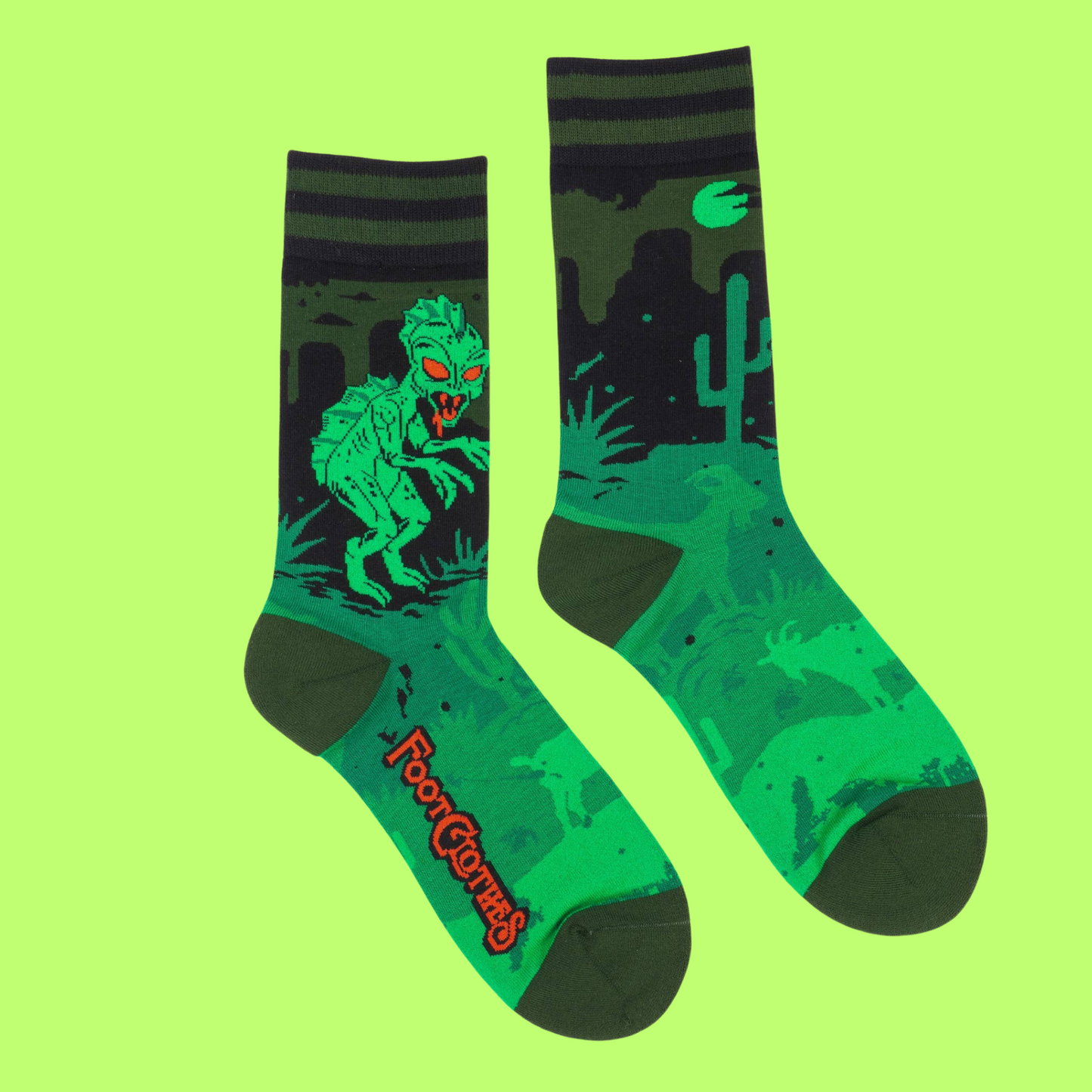 A pair of socks featuring El Chupacabra. Green legs, heel, toe and cuff.