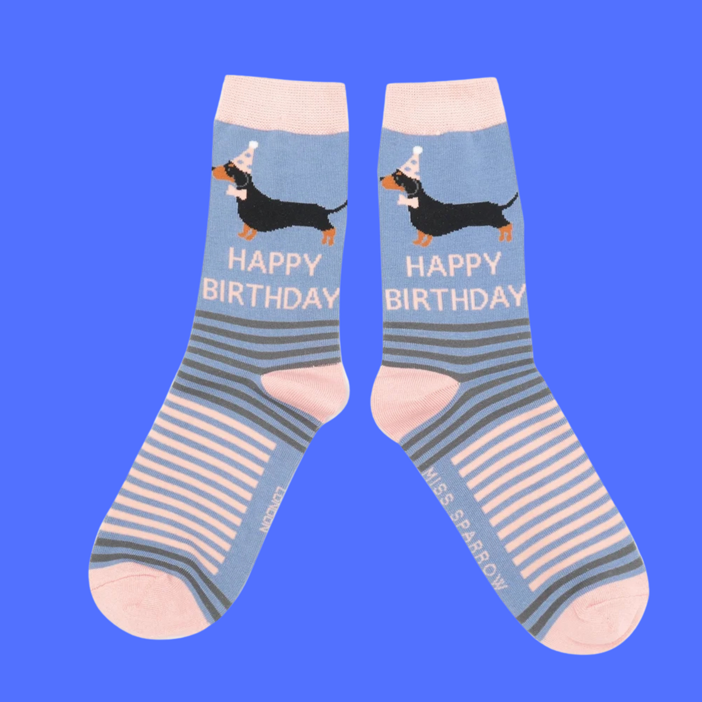 A pair of socks featuring sausage dogs all dressed up for a party. Blue legs, Pink heel heel, toe and cuff.