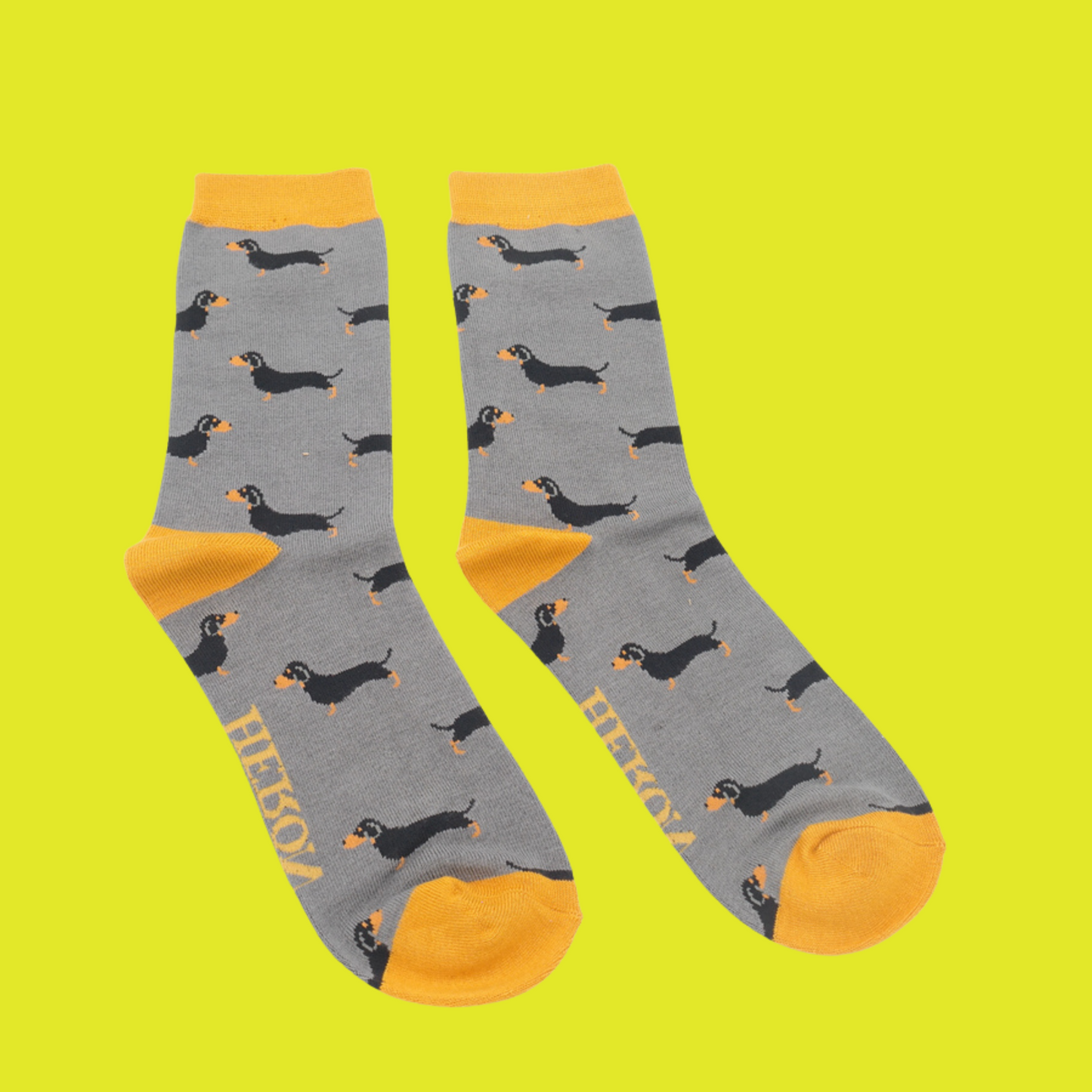 A pair of socks featuring a sausage dog pattern. Grey legs, yellow cuffs, heel and toe.
