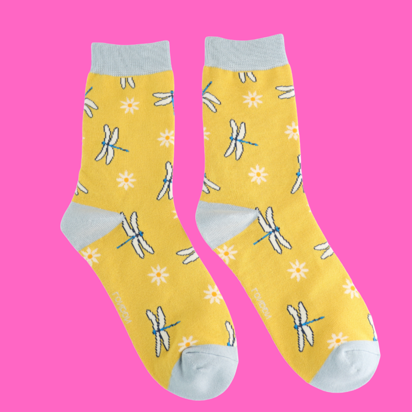 Dragonflies and Daisies Bamboo Socks - Miss Sparrow. A pair of yellow socks featuring a daisy and dragonfly pattern. Pale blue cuffs, heels, and toes. Socks shown on a pink background.