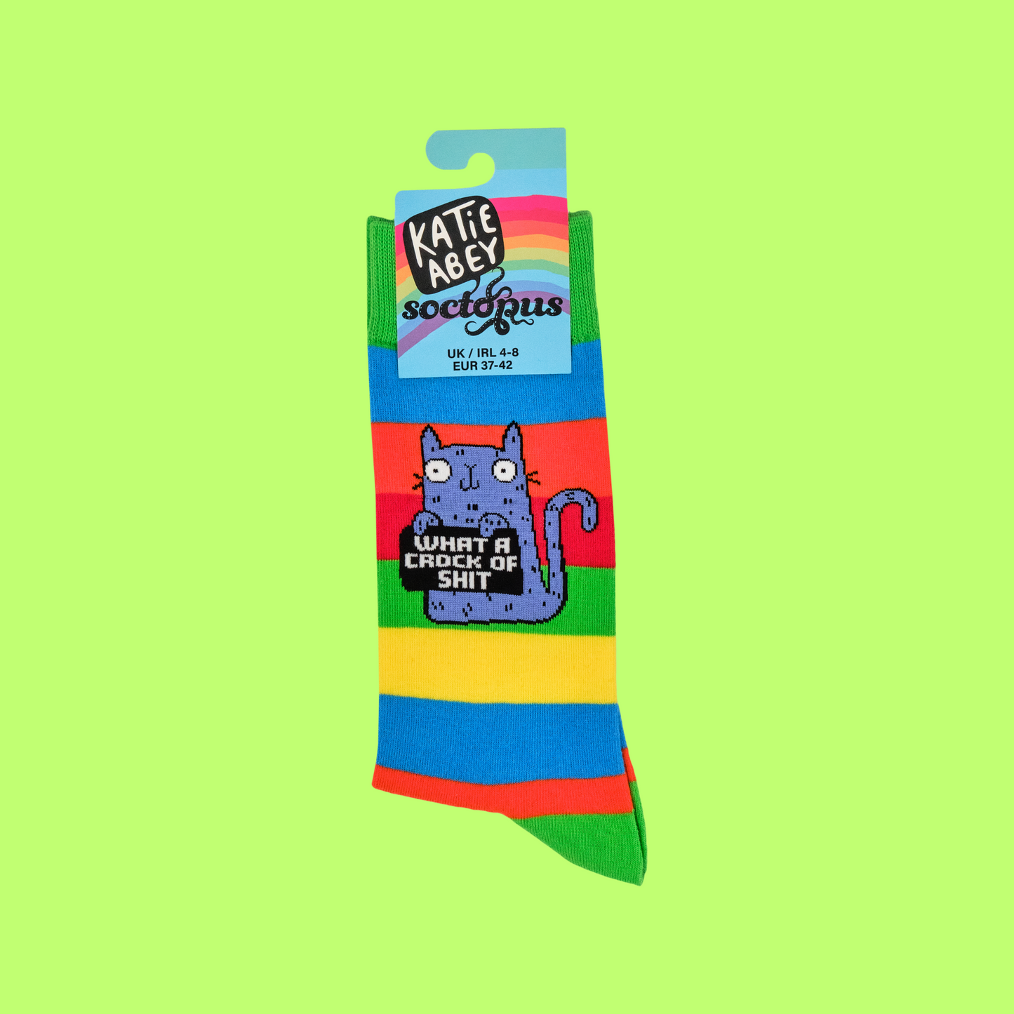 A pair of socks featuring a cute cat holding a sweary sign. Multicolored striped legs.