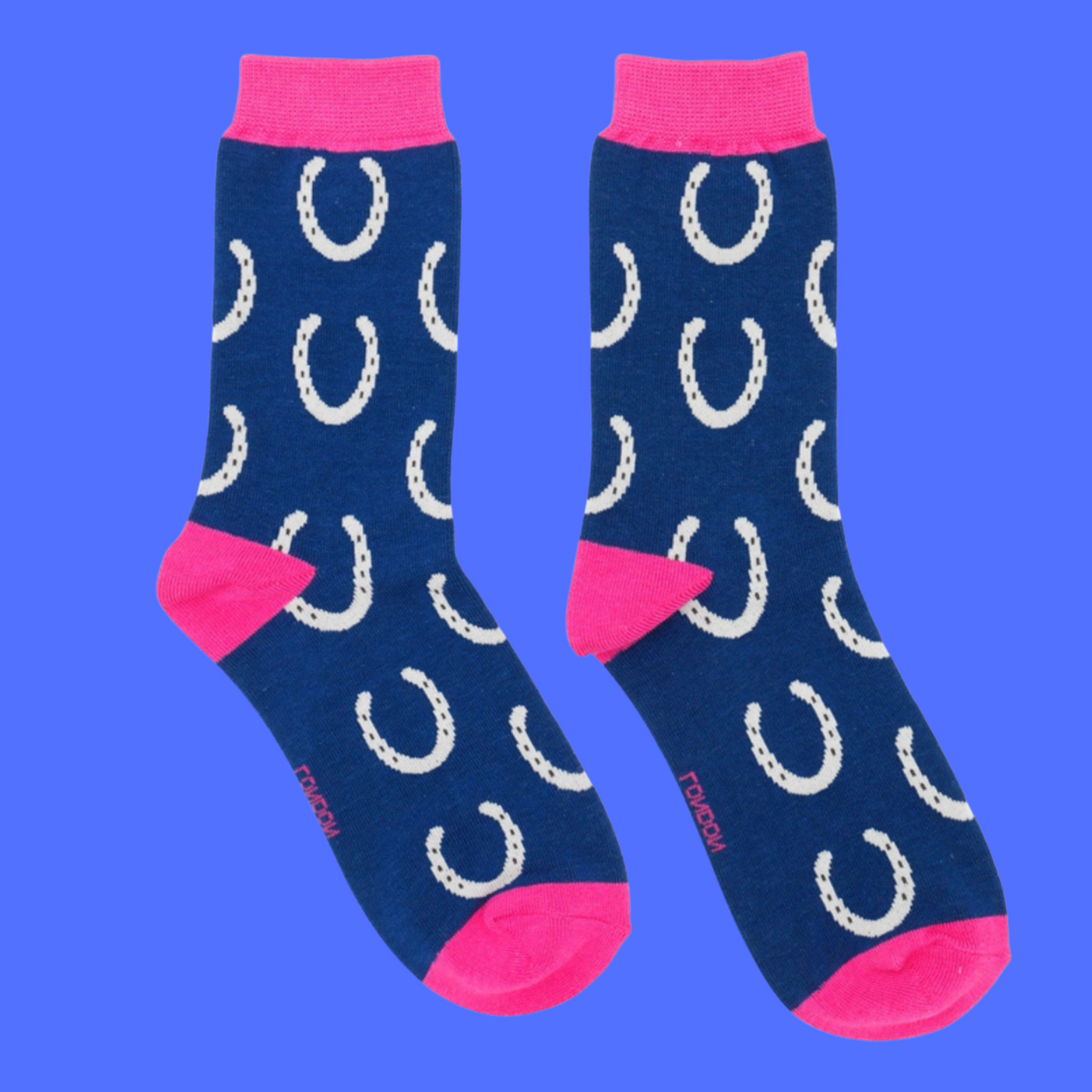 Horseshoes Bamboo Socks - Miss Sparrow. A pair of navy socks featuring a white horseshoe pattern. Bright pink cuffs, heels, and toes. Socks shown on a purple background.