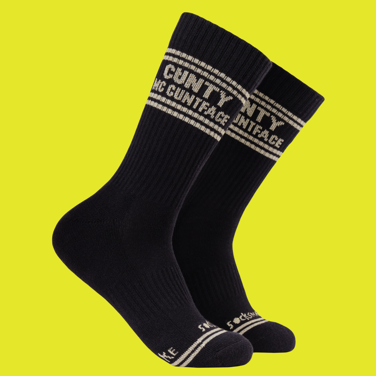 A black pair of athletic socks with white trim on the ankles and toes. With some very rude words on the ankle.
