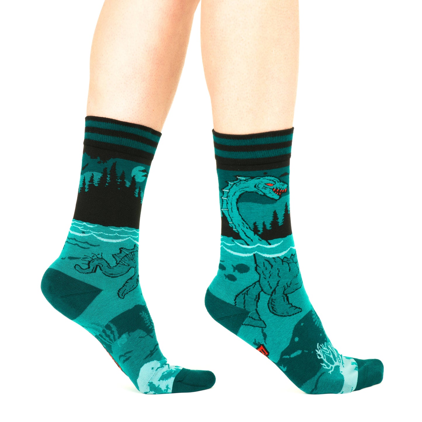 A model wearing a pair of socks featuring the Loch Ness Monster. Blue legs, blue heel, toe and cuff.