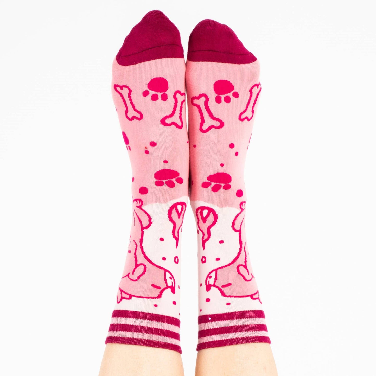 A model wearing a pair of socks featuring a cute 3 headed dog. Pink legs, dark pink heel, toe and cuff.