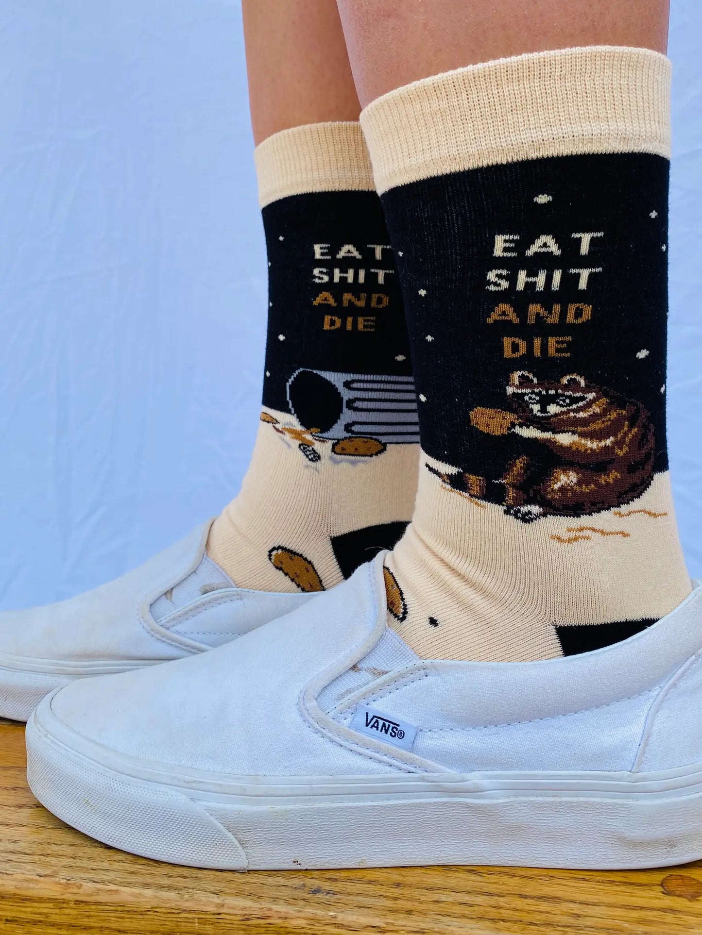 Model wearing pair of socks with a bold slogan and racoon eating out of the bin detail. Black toe, cuff and heel.