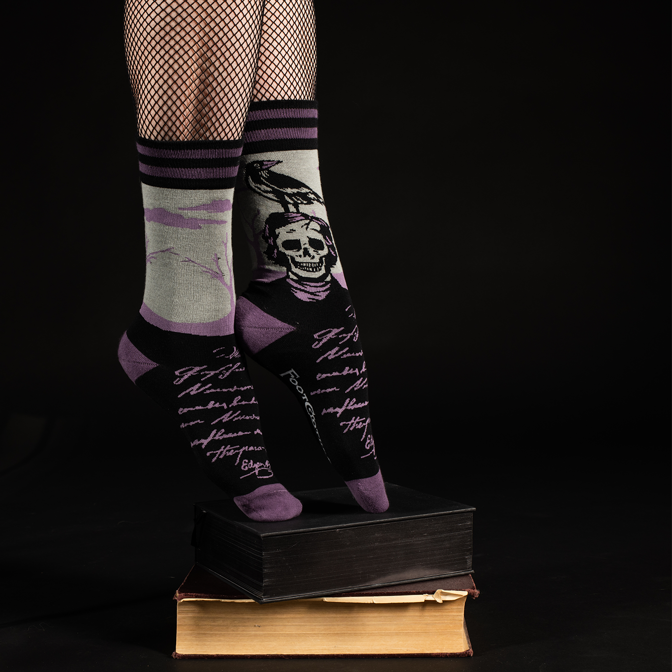 A pair of socks depicting a skeleton Edgar Allan Poe with a raven. Purple toes, heel and cuff.
