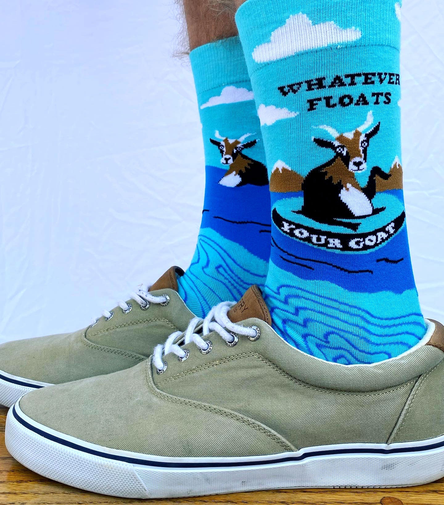 A model wearing a pair of socks depicting a floating goat and a fun slogan. Brown toes, cuffs and heel.