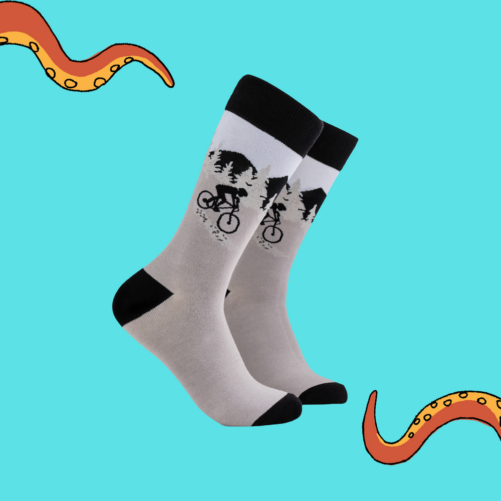 A pair of socks depicting a mountain biker. Grey legs, black heel toe and cuff. 
