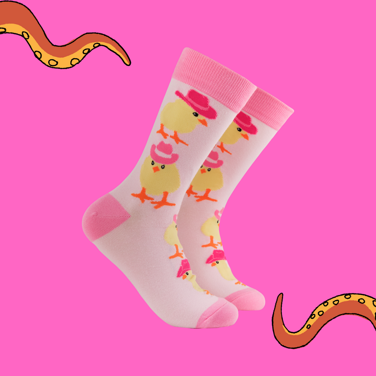 A pair of socks with a chick in cowboy hats motif. Light pink legs, dark pink heel, toe and cuff. 