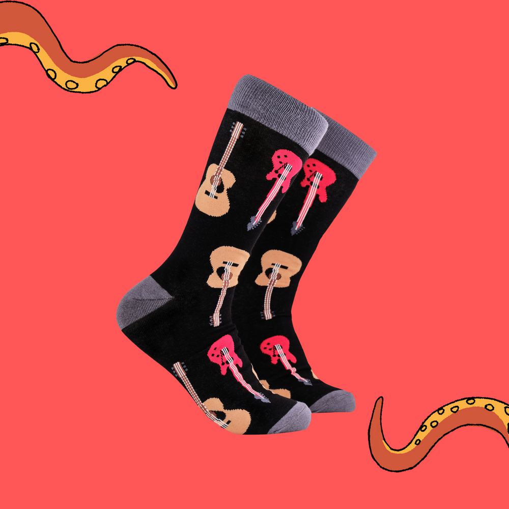 A pair of socks depicting electric and acoustic guitars. Black legs, grey cuff, heel and toe.