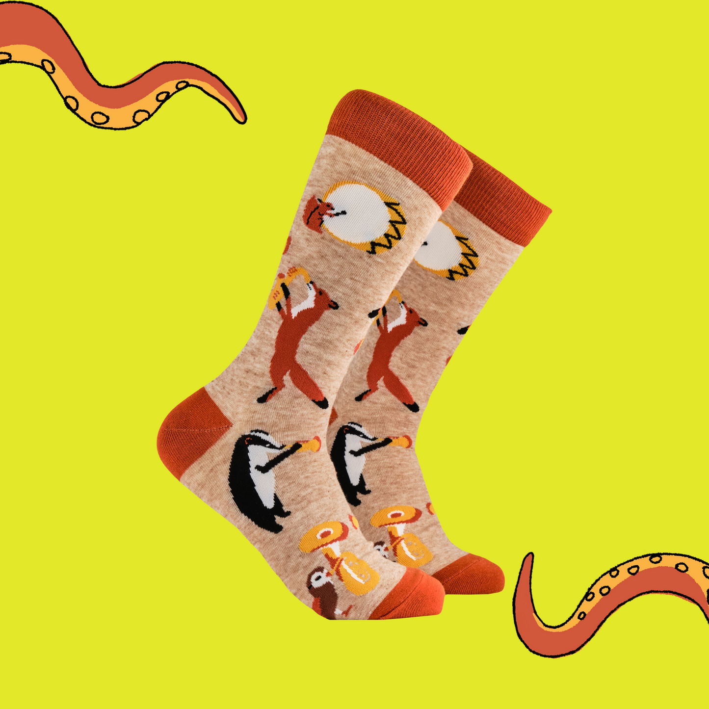 A pair of socks featuring some woodland creatures playing musical instruments. Brown legs, orange cuff, toe and heel. 