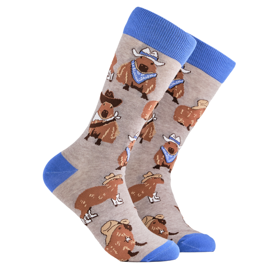 Cowboy Capybara Socks. A pair of socks depicting Capybaras wearing cowboy hats. Grey legs, blue cuff, heel and toe.
