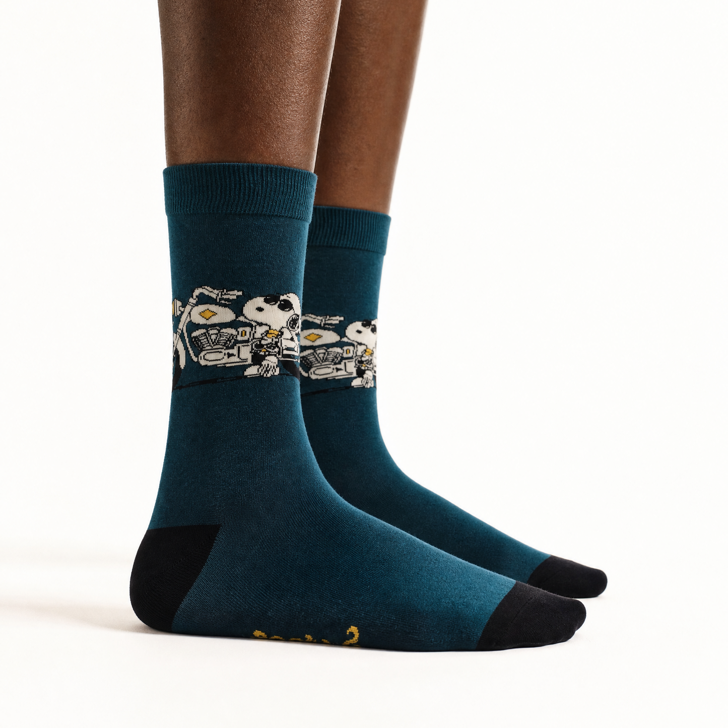 A pair of crew socks featuring Snoopy, worn on a person's feet, shown against a plain white studio background. 