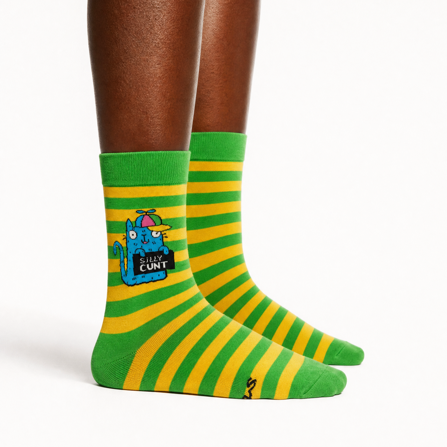 A pair of green and yellow striped crew socks with a cartoon graphic on the left sock, shown on a model's feet against a white background.