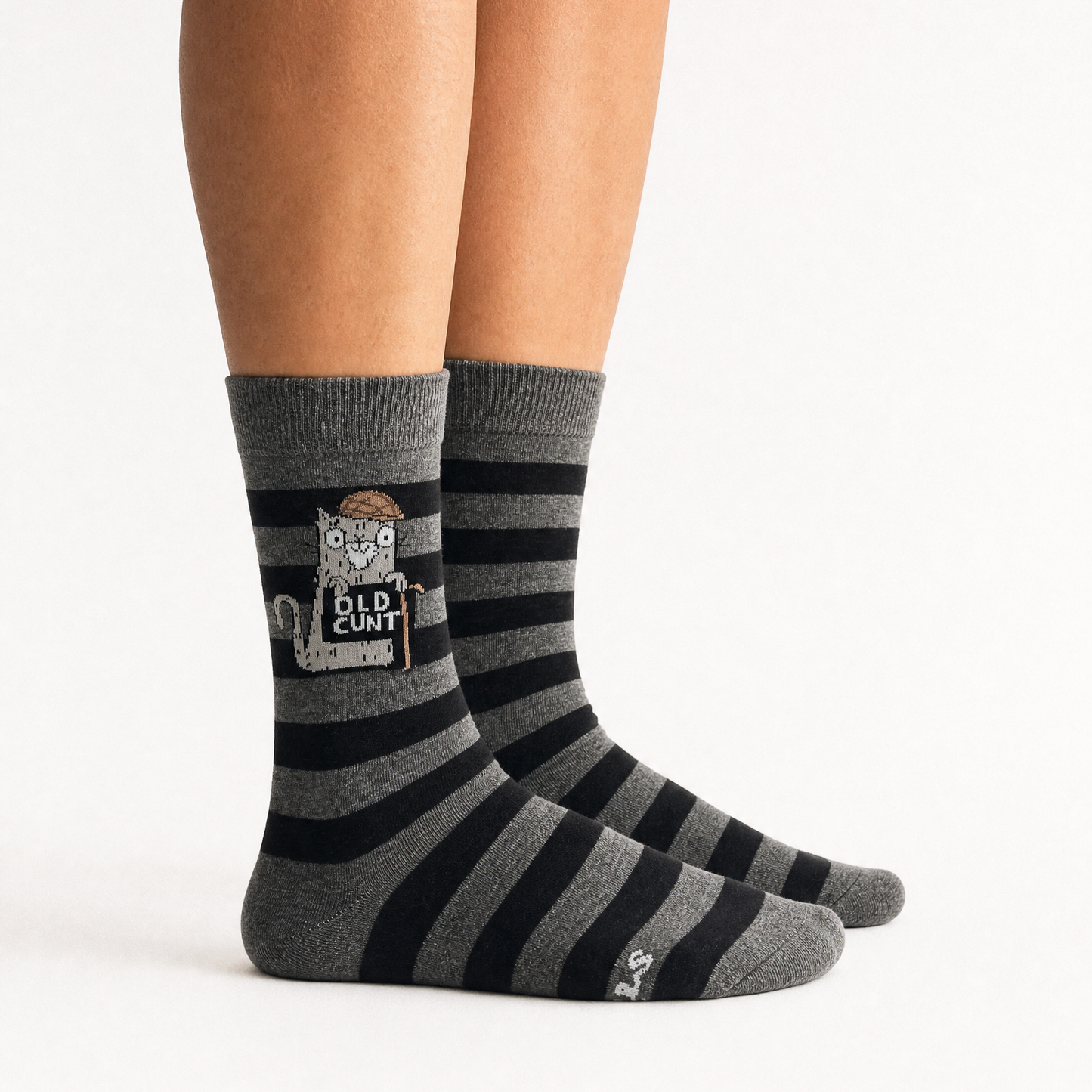 A person's legs wearing gray and black striped crew socks with a cartoon owl graphic and the text 'OLD CUNT' on the front sock, against a plain white background.