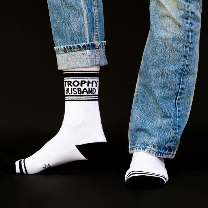 A pair of black and white sports style socks with a Trophy Husband slogan. 