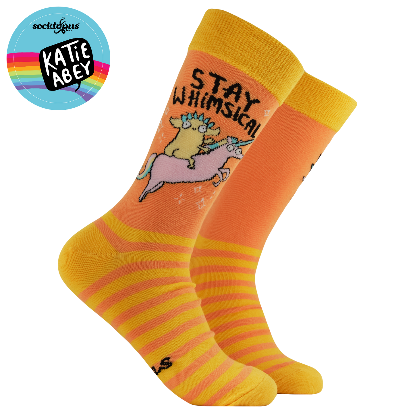 Orange and yellow socks with a cartoon cow on a unicorn, featuring the text 'Stay Whimsical', on a white background.