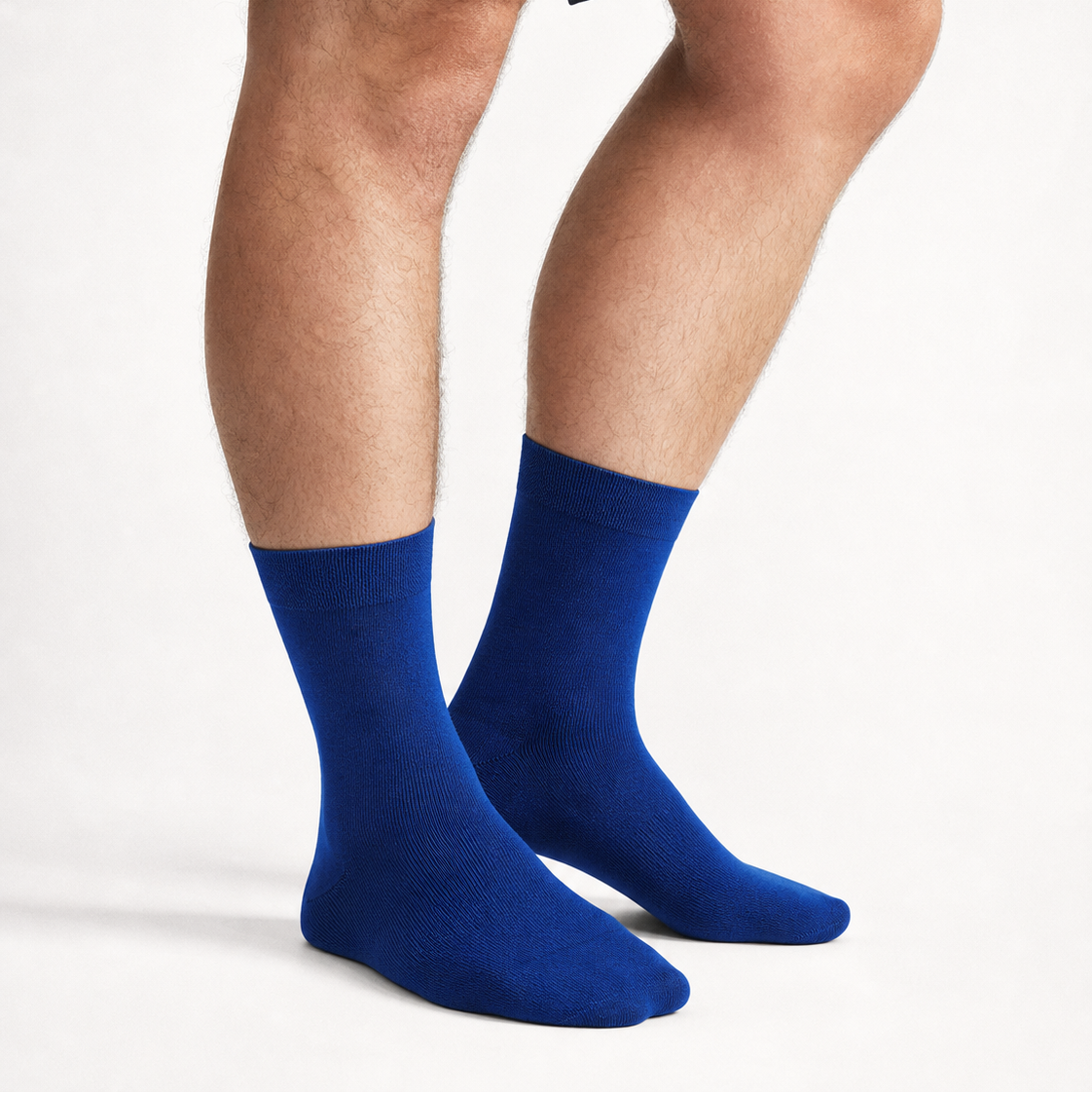 A person wearing bright royal blue crew socks, shown from the thighs down against a clean white studio background.