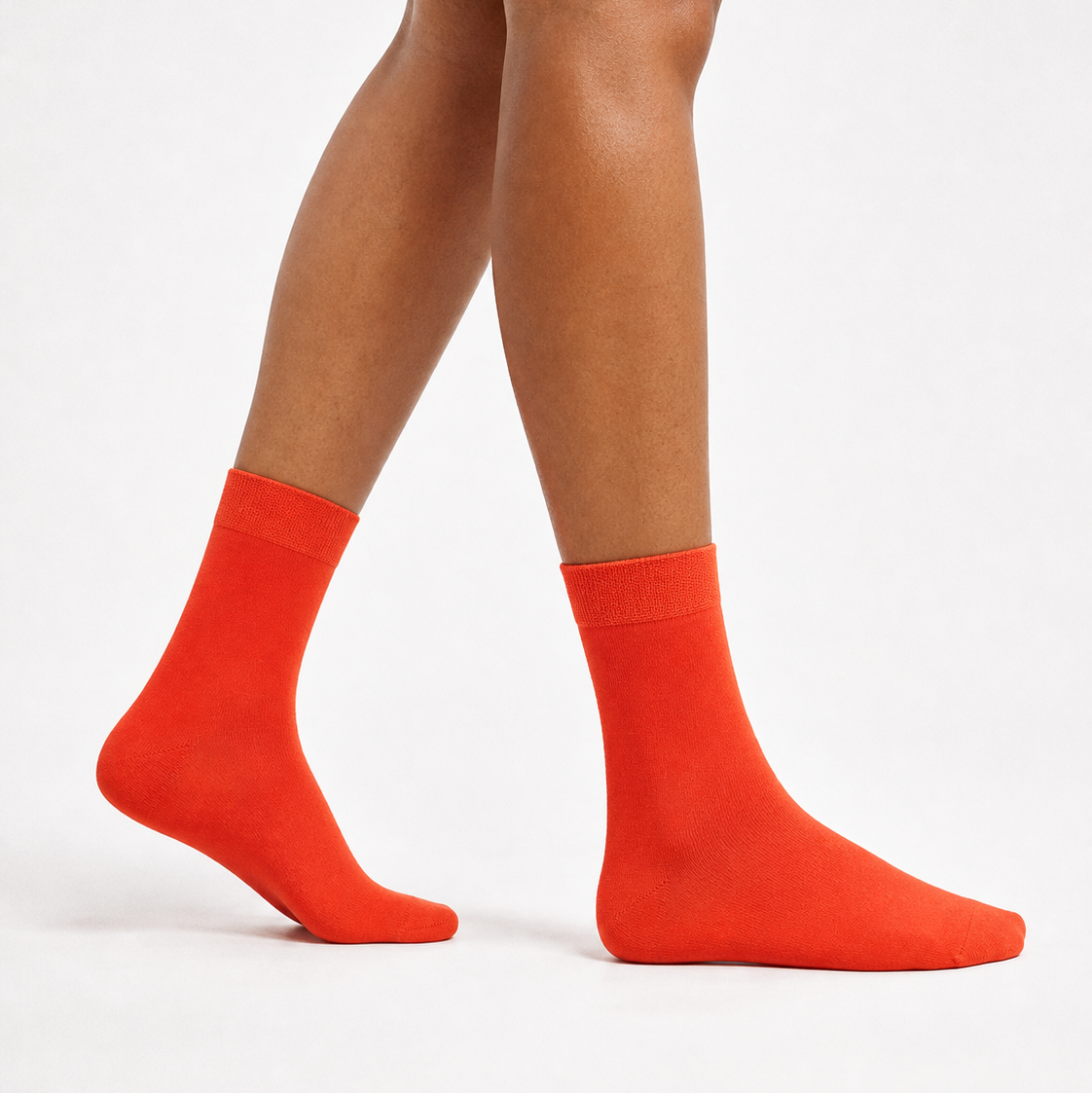 Bright orange crew socks worn on a model's feet, shown from the calves down against a clean white studio background.